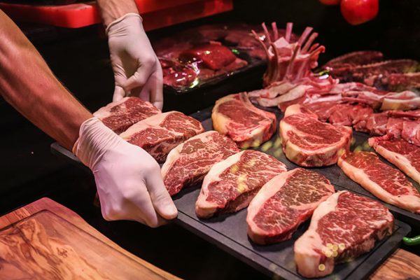 side view the chef makes preforms raw marbled beef for steaks on a stand